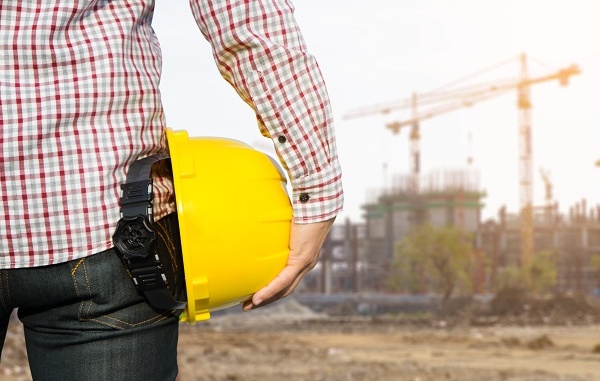 Hand's engineer worker holding yellow safety helmet with buildin